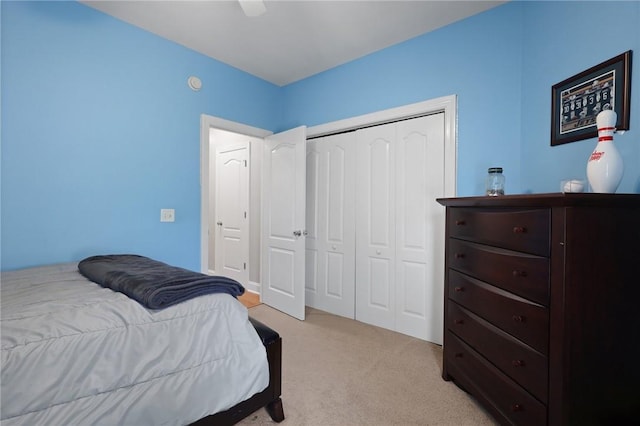 bedroom with ceiling fan, light carpet, and a closet
