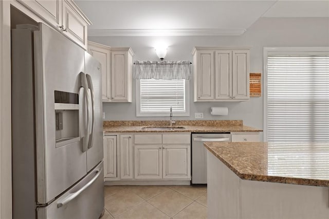kitchen featuring crown molding, light tile patterned flooring, light stone countertops, a sink, and stainless steel appliances