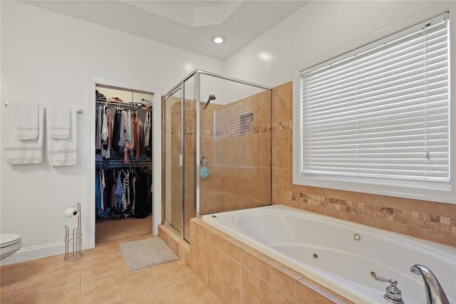 bathroom featuring a jetted tub, a walk in closet, tile patterned flooring, a stall shower, and toilet