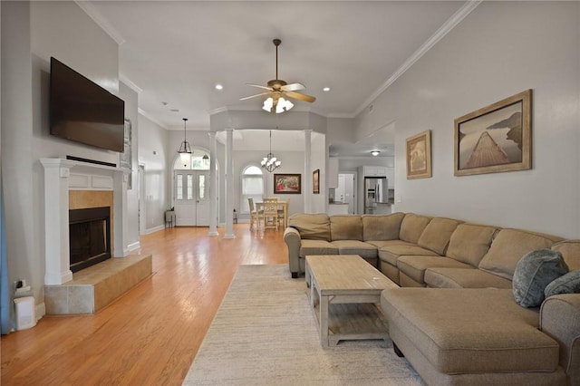 living area featuring recessed lighting, ornamental molding, light wood-style flooring, and ceiling fan with notable chandelier