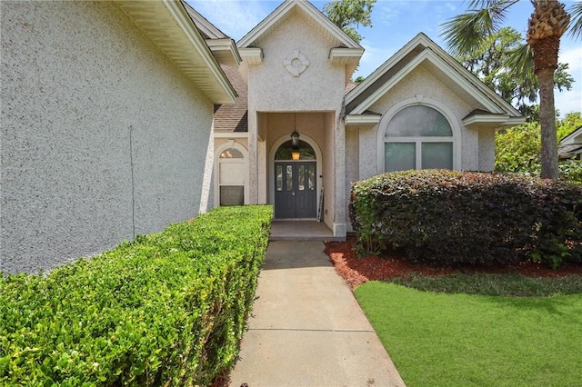 property entrance featuring stucco siding and a yard