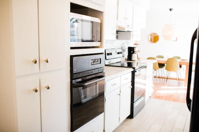 kitchen with backsplash, pendant lighting, black oven, white cabinets, and range