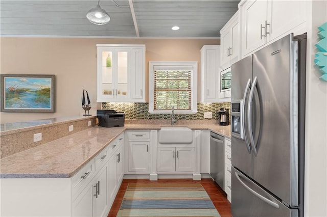 622 Beachview Dr, Saint Simons Island, GA 31522 - kitchen featuring appliances with stainless steel finishes, a peninsula, dark wood finished floors, white cabinets, and tasteful backsplash