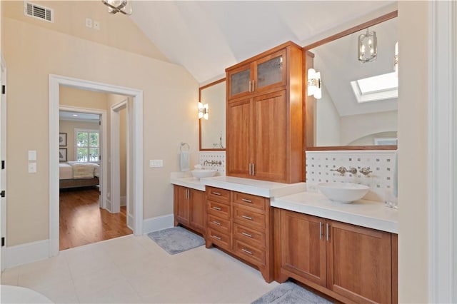 622 Beachview Dr, Saint Simons Island, GA 31522 - bathroom featuring vaulted ceiling, a skylight, double vanity, ensuite bath, and tasteful backsplash
