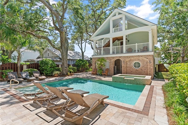 622 Beachview Dr, Saint Simons Island, GA 31522 - rear view of property featuring a fenced backyard, a patio area, a balcony, brick siding, and a pool with connected hot tub