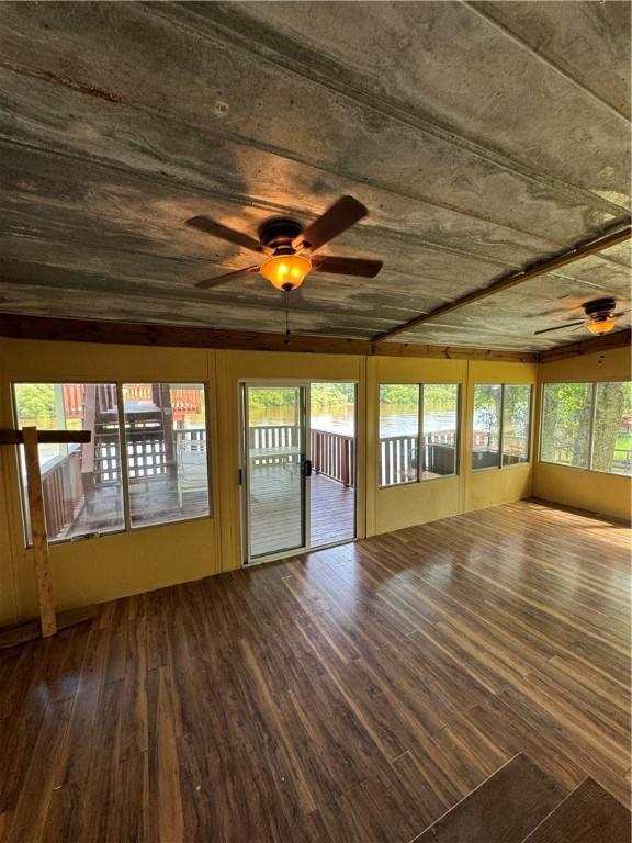 unfurnished sunroom featuring ceiling fan and a healthy amount of sunlight