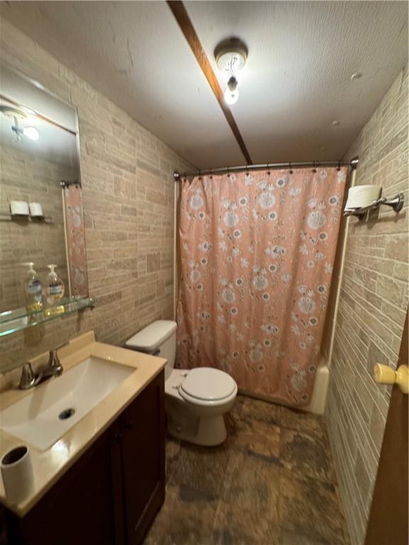 bathroom with vanity, brick wall, and toilet