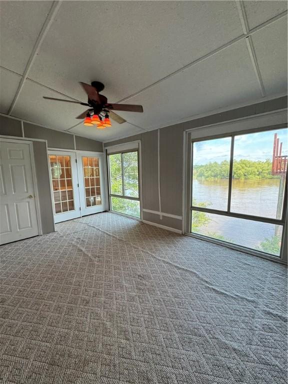 spare room featuring a water view, carpet floors, and a wealth of natural light