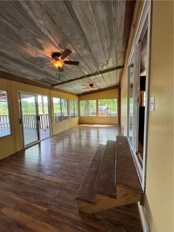 unfurnished sunroom featuring a wealth of natural light, ceiling fan, wood ceiling, and lofted ceiling