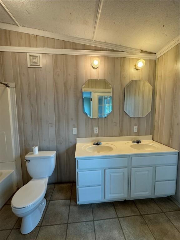 full bathroom featuring vanity, crown molding, wooden walls, tile patterned flooring, and toilet