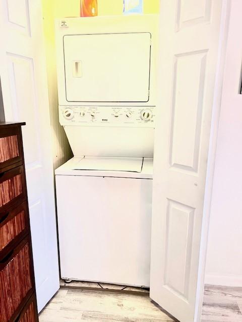 washroom featuring light hardwood / wood-style flooring and stacked washing maching and dryer