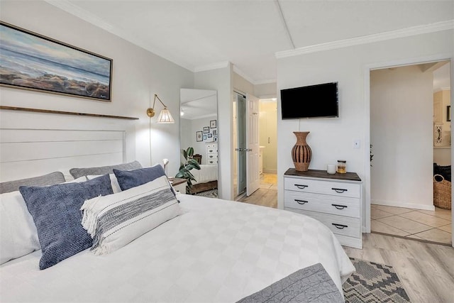 bedroom with ensuite bathroom, crown molding, and light wood-type flooring