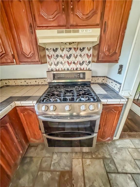 209 Lewis Dr, Rincon, GA 31326 - kitchen with range with two ovens, under cabinet range hood, tile countertops, and brown cabinets