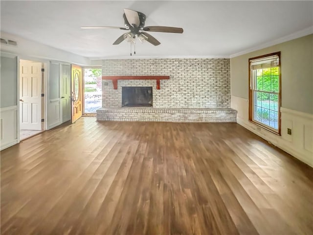 209 Lewis Dr, Rincon, GA 31326 - unfurnished living room featuring wainscoting, a ceiling fan, brick wall, wood finished floors, and crown molding