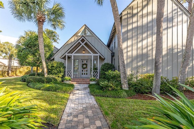 property entrance with a lawn, board and batten siding, and french doors