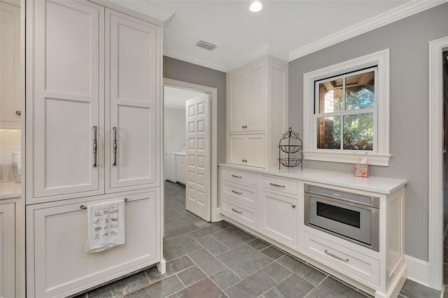 kitchen with visible vents, ornamental molding, built in microwave, light countertops, and white cabinetry