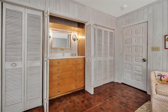 bedroom featuring wooden walls and two closets