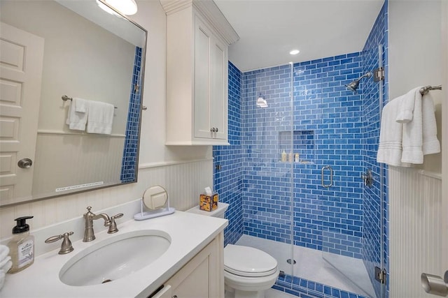 bathroom featuring toilet, a wainscoted wall, a shower stall, and vanity