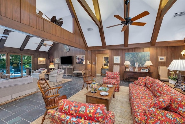 living room with wood walls, beam ceiling, visible vents, and a ceiling fan