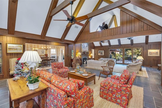 living room with stone tile flooring, a fireplace, wood walls, and beamed ceiling