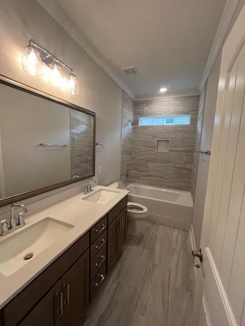 bathroom featuring toilet, double vanity, shower / tub combination, and ornamental molding