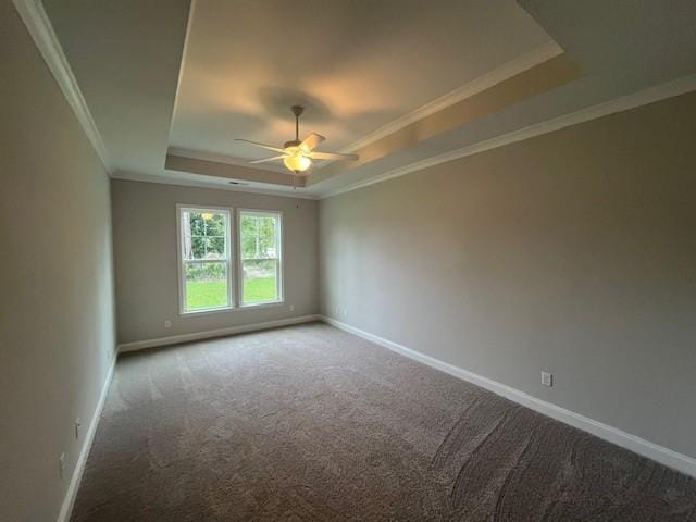 carpeted empty room featuring a tray ceiling, ceiling fan, baseboards, and ornamental molding