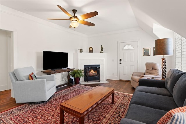 living room featuring baseboards, ceiling fan, wood finished floors, and a tile fireplace
