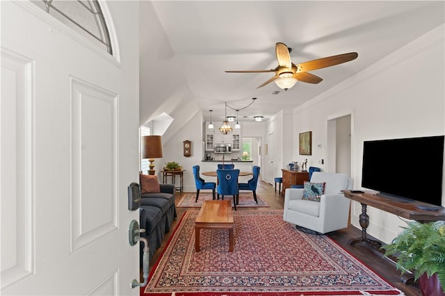 living room with a ceiling fan, ornamental molding, and wood finished floors