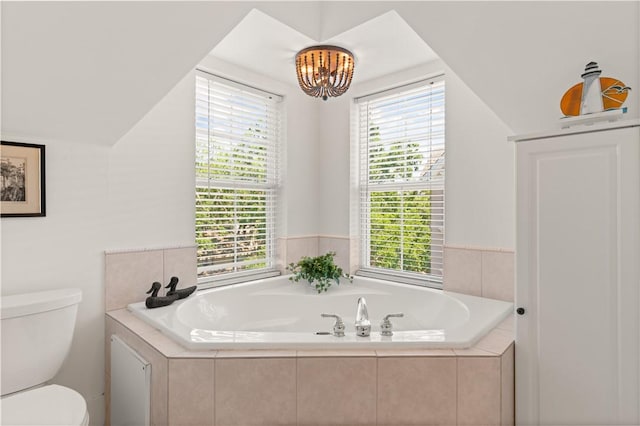 bathroom with toilet, an inviting chandelier, plenty of natural light, and a garden tub