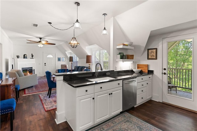 kitchen featuring stainless steel dishwasher, dark countertops, visible vents, and a sink
