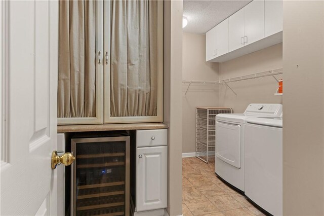 laundry room with cabinets, a textured ceiling, washing machine and dryer, wine cooler, and light tile patterned flooring