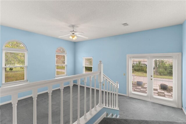 hallway with a textured ceiling, carpet floors, and a healthy amount of sunlight