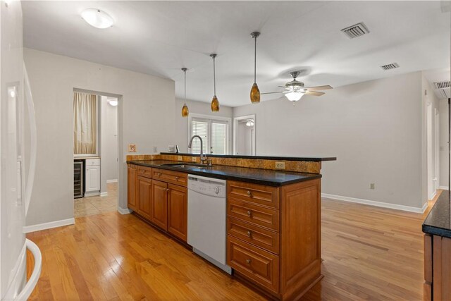 kitchen featuring light wood-type flooring, white appliances, beverage cooler, sink, and hanging light fixtures