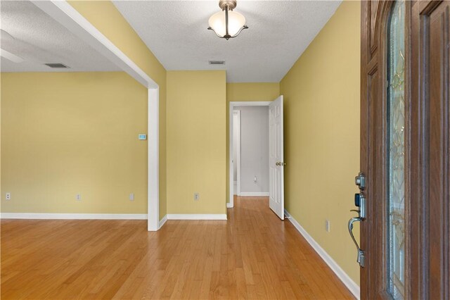 entrance foyer with a textured ceiling and light hardwood / wood-style flooring