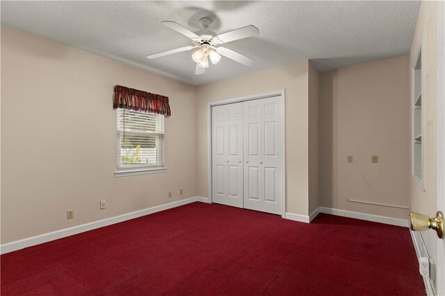 unfurnished bedroom featuring ceiling fan, dark carpet, a textured ceiling, and a closet