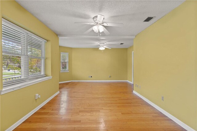 empty room featuring ceiling fan, light hardwood / wood-style floors, and a textured ceiling