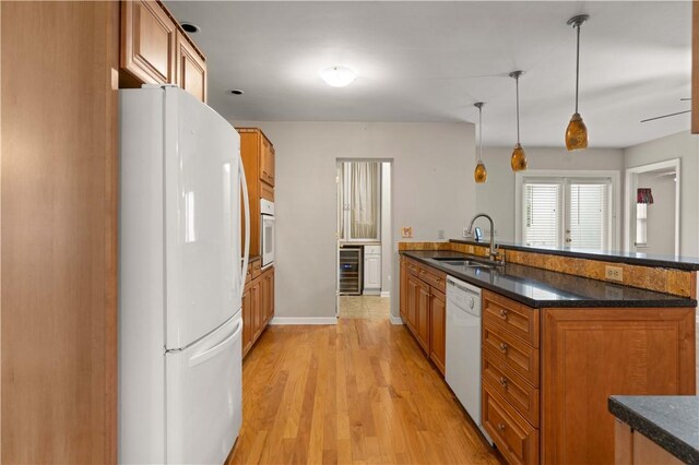 kitchen with white appliances, sink, light hardwood / wood-style flooring, decorative light fixtures, and beverage cooler