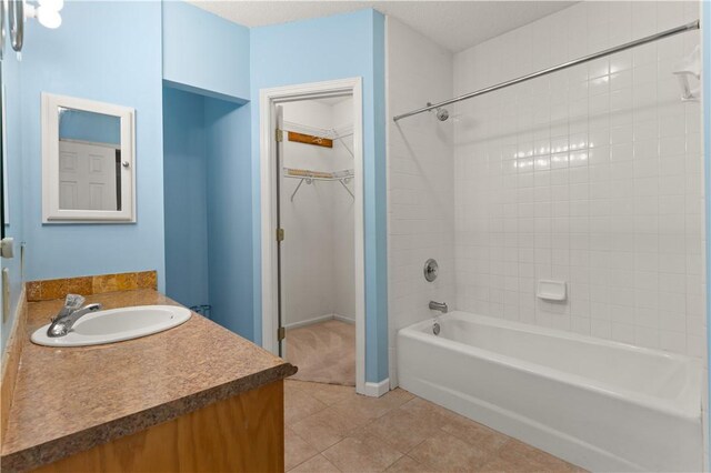 bathroom with tile patterned flooring, vanity, tiled shower / bath, and a textured ceiling