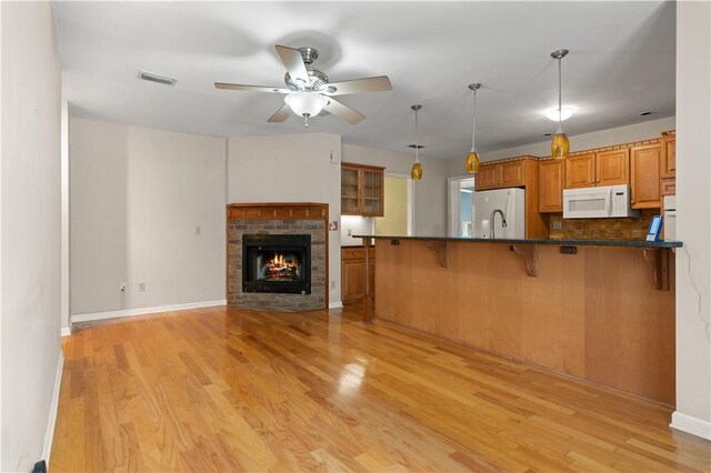 kitchen featuring a brick fireplace, decorative light fixtures, white appliances, and light hardwood / wood-style flooring