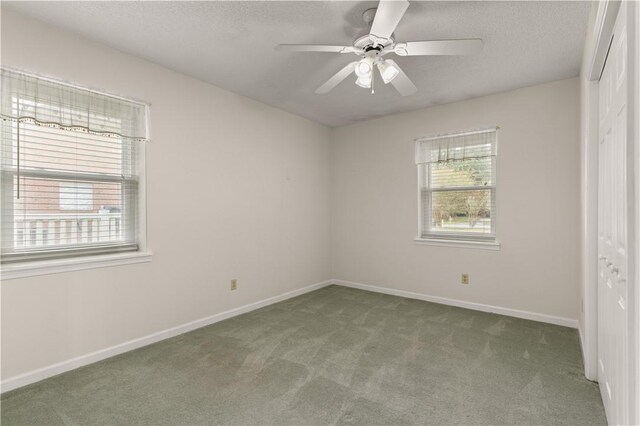 carpeted empty room featuring ceiling fan, a healthy amount of sunlight, and a textured ceiling