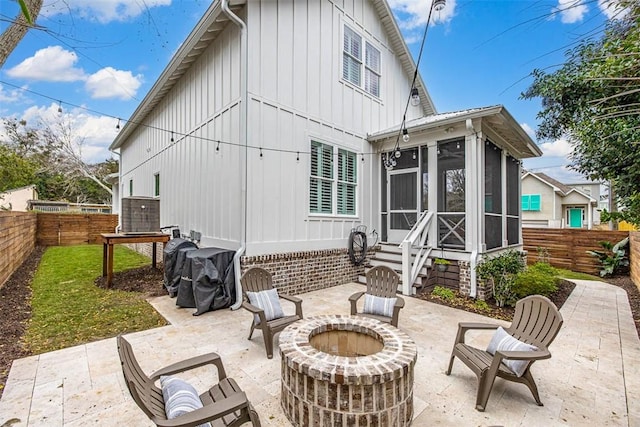 back of house with a sunroom, a patio, and a fire pit