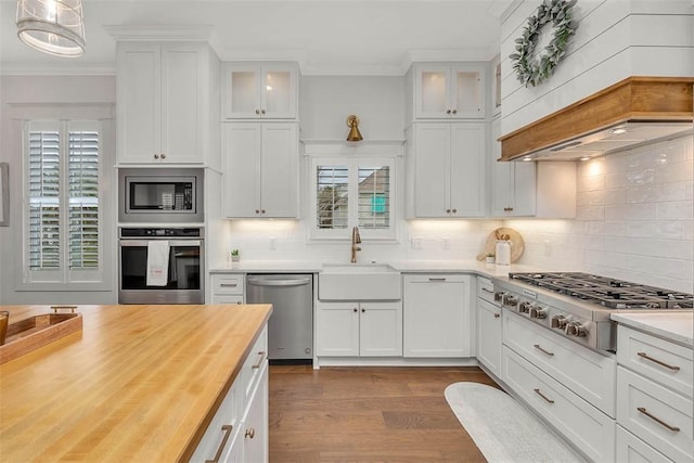 kitchen with white cabinetry, sink, wood counters, decorative light fixtures, and appliances with stainless steel finishes