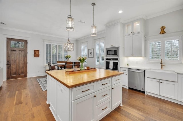 kitchen featuring sink, hanging light fixtures, a kitchen island, white cabinetry, and stainless steel appliances