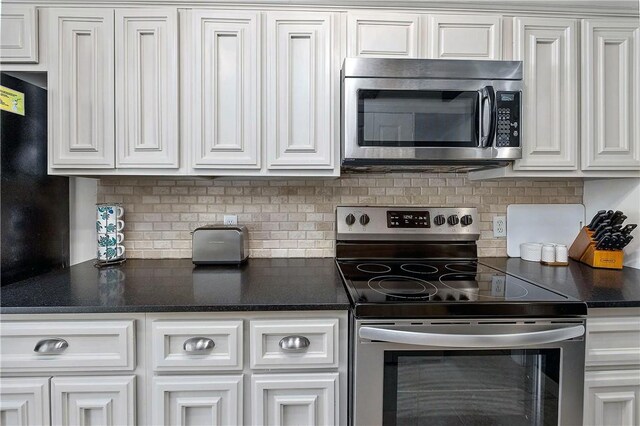 kitchen with white cabinets, appliances with stainless steel finishes, and tasteful backsplash