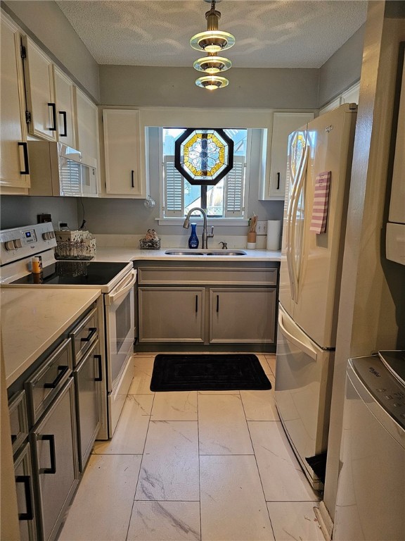 kitchen with refrigerator, sink, electric range, a notable chandelier, and white cabinets