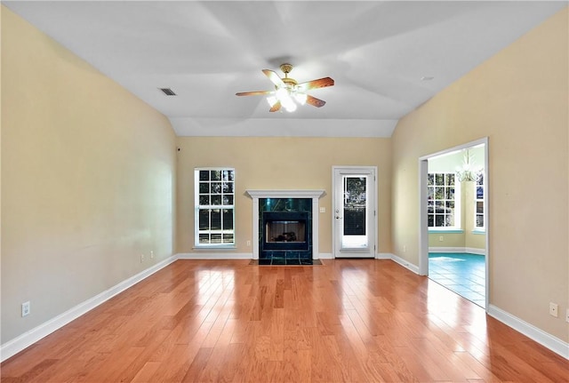 unfurnished living room featuring ceiling fan, light hardwood / wood-style floors, lofted ceiling, and a premium fireplace