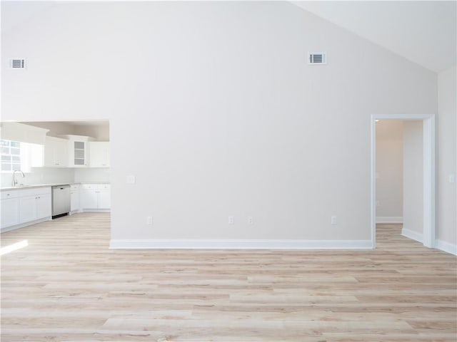 unfurnished living room featuring sink, high vaulted ceiling, and light wood-type flooring