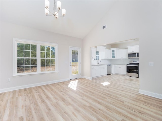 interior space featuring an inviting chandelier, high vaulted ceiling, light hardwood / wood-style flooring, and sink