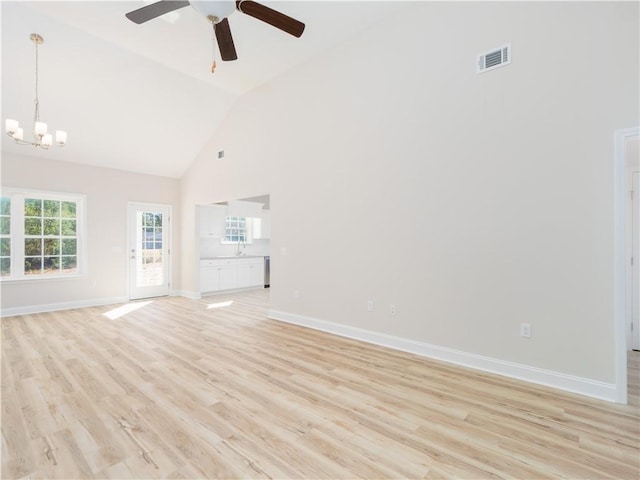 unfurnished living room with light hardwood / wood-style flooring, high vaulted ceiling, ceiling fan with notable chandelier, and sink