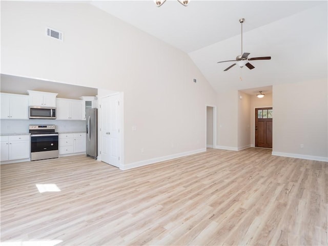 unfurnished living room with high vaulted ceiling, light hardwood / wood-style floors, and ceiling fan with notable chandelier